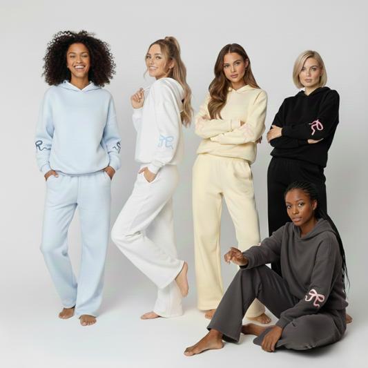 Pięć kobiet w dresach Luna™ Ribbon Tracksuit z Inicala.pl w pastelowych i klasycznych kolorach pozuje razem na jasnym tle, pokazując różne sylwetki i rozmiary w tym samym wygodnym kroju