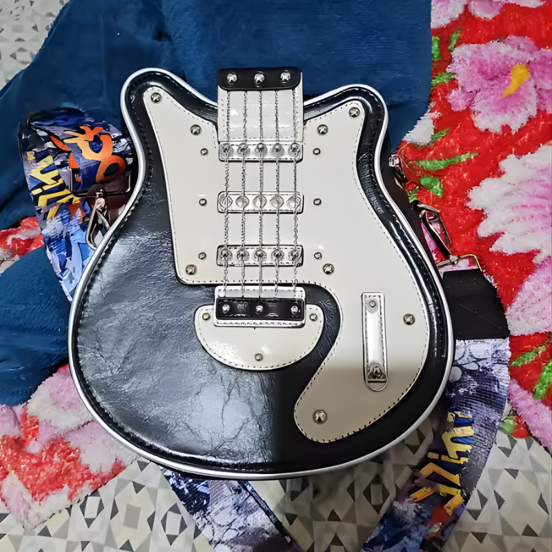 Czarno biala Guitarista Torebka Crossbody z kolorowym paskiem ROCK lezy na kocu widoczne blyszczace przeszycia i lancuszki produkt Inicala.pl
