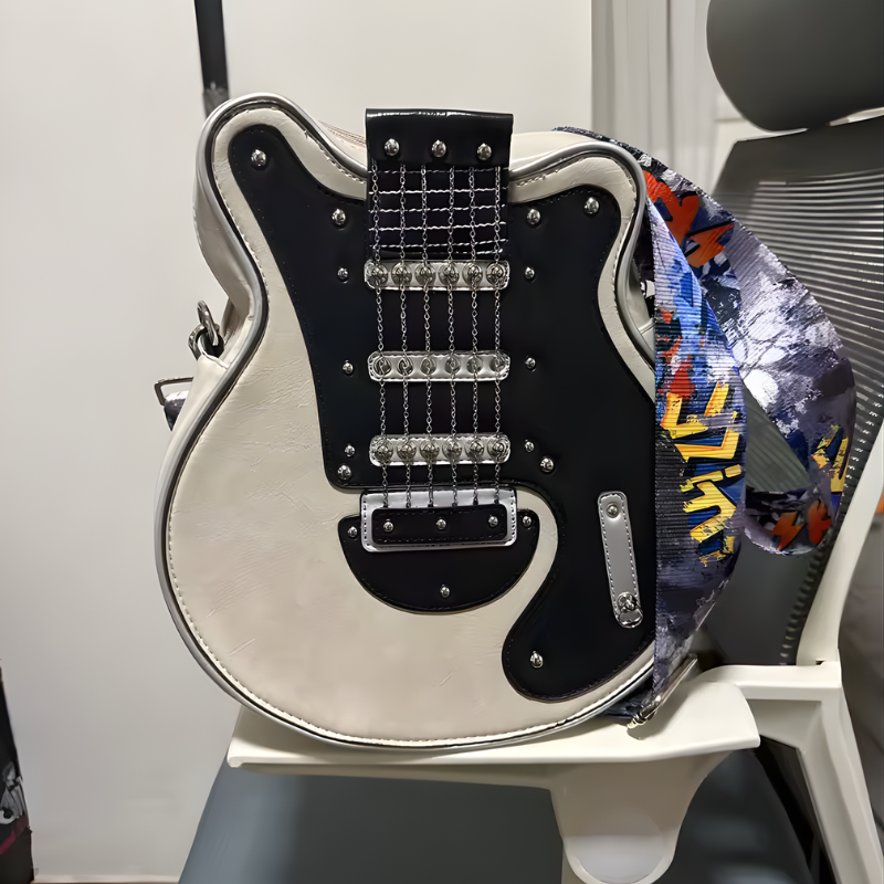 Jasna kremowa Guitarista Torebka Crossbody z czarnym frontem w ksztalcie gitary oparta o krzeslo biurowe prezentacja produktu Inicala.pl