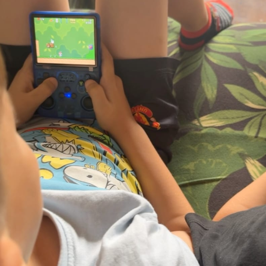 PixelPlay™ Legends od Inicala.pl w rękach dziecka. Niebieska konsola retro z klasyczną grą platformową na ekranie. Idealna rozrywka w domu i w podróży, bez internetu.