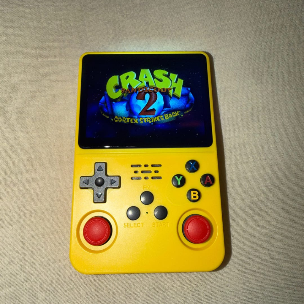 PixelPlay™ Legends od Inicala.pl w żółtej wersji kolorystycznej. Na ekranie Crash Bandicoot 2. Mała konsola retro z wygodnym sterowaniem i tysiącami klasycznych gier w jednym urządzeniu.