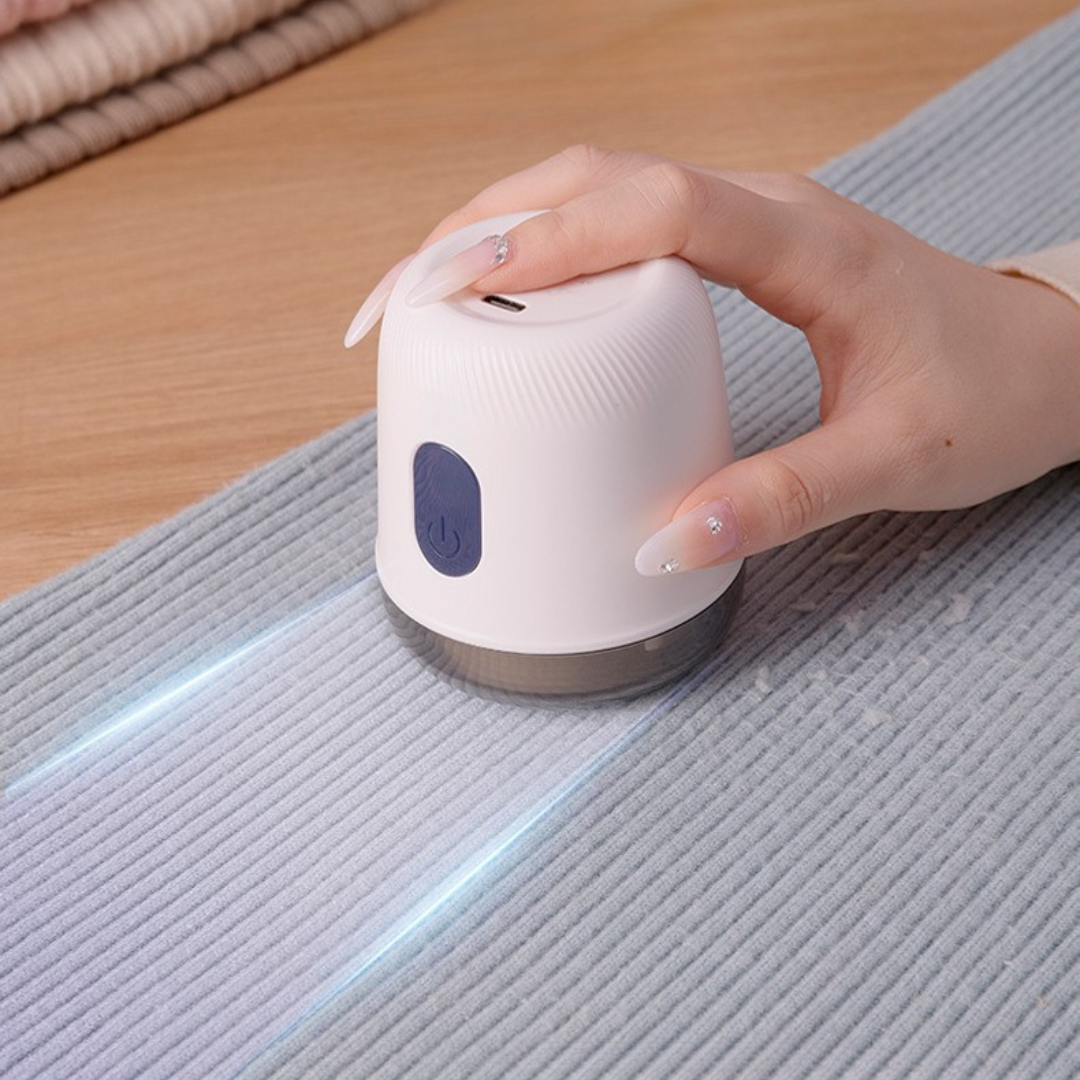 Ręka trzymająca Fuzora™ z Inicala.pl podczas czyszczenia swetra – urządzenie skutecznie usuwa kłaczki i przywraca tkaninom gładkość oraz świeży wygląd